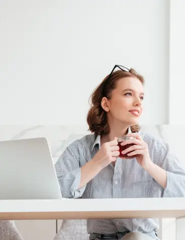 Mujer sentada sosteniendo una taza con sus dos manos mirando a su izquierda